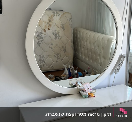 מראה עגולה על שידה עם מוצרי טיפוח